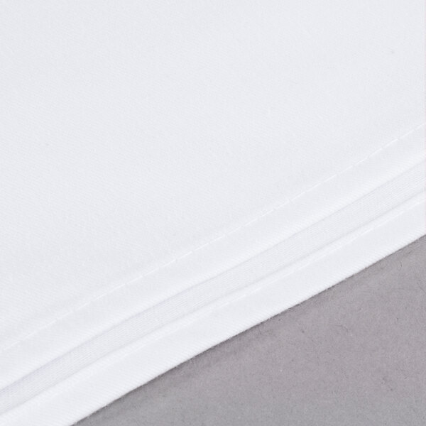 A close up of a stack of white Intedge square table covers.