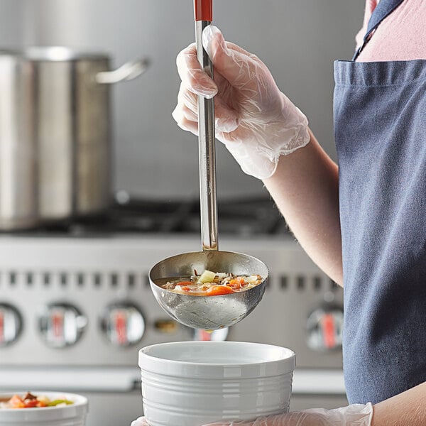 A woman using a Vollrath ladle to serve soup into a white bowl.