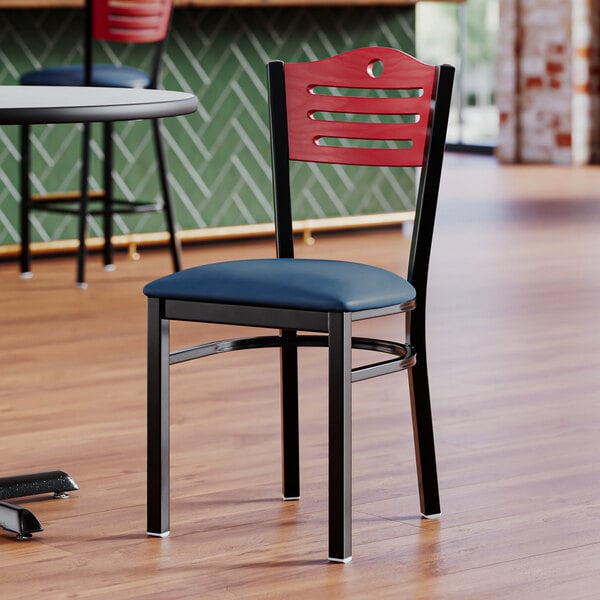 A Lancaster Table & Seating black chair with a navy vinyl seat and mahogany wood back on a table in a restaurant dining area.