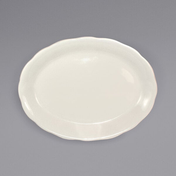 A white International Tableware Victoria scalloped edge stoneware platter on a gray surface.