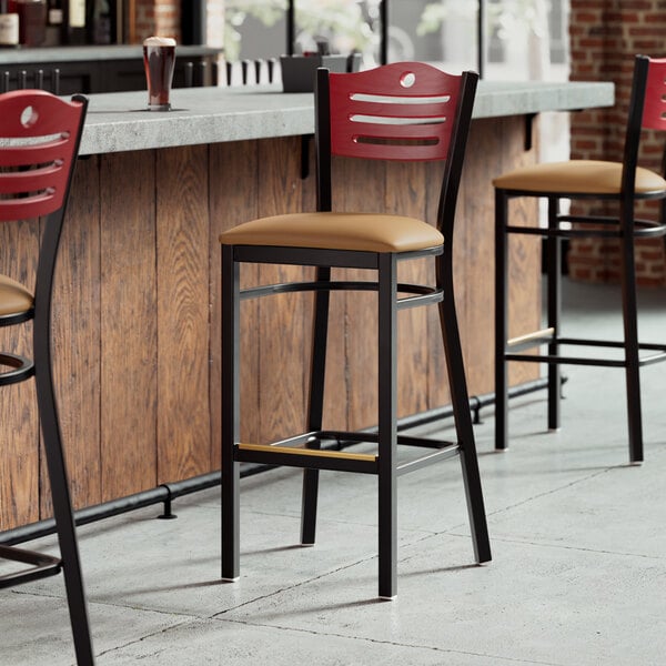 A Lancaster Table & Seating bar stool with a light brown vinyl seat and mahogany back.