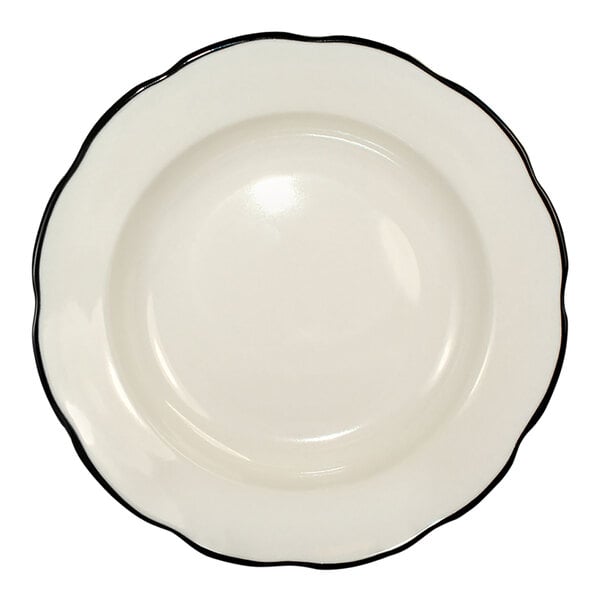 A round ivory stoneware pasta bowl with a scalloped edge and a black rim.