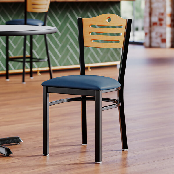 A Lancaster Table & Seating side chair with navy vinyl seat and natural wood back with blue cushion.