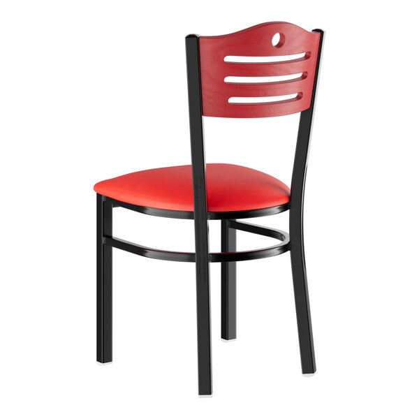 A red and black metal Lancaster Table & Seating side chair with mahogany wood back and red vinyl seat.