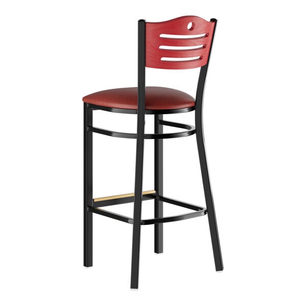 A black Lancaster Table & Seating restaurant bar stool with mahogany accents and a red vinyl seat.