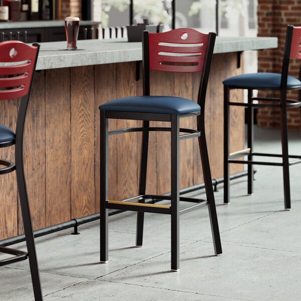 The detached navy vinyl seat and mahogany wood back of a Lancaster Table & Seating bar stool.