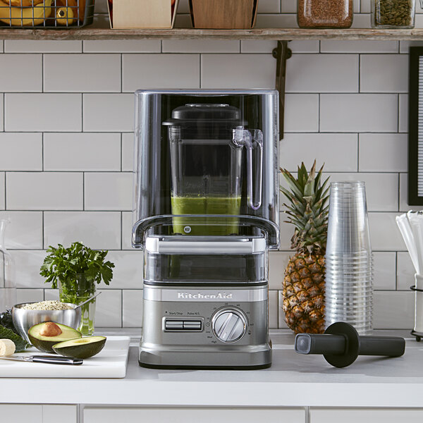 A KitchenAid commercial blender with enclosure on a counter.