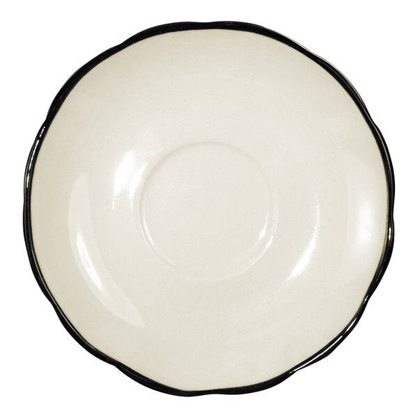 An ivory stoneware saucer with a scalloped edge and a black rim.