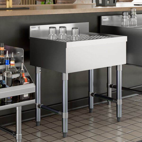 A stainless steel underbar drainboard with four glasses placed upside down on top.