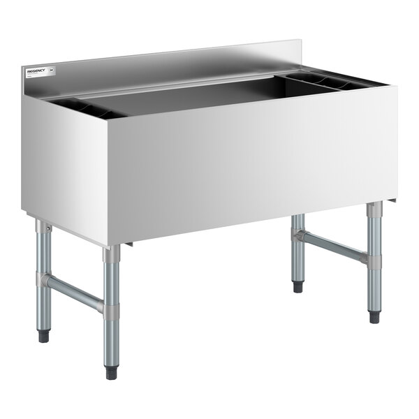 A stainless steel underbar ice bin with a backsplash, bottle holders, and sturdy metal legs.