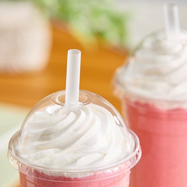 A translucent pointed smoothie straw inserted into a plastic cup with a dome lid and whipped topping.