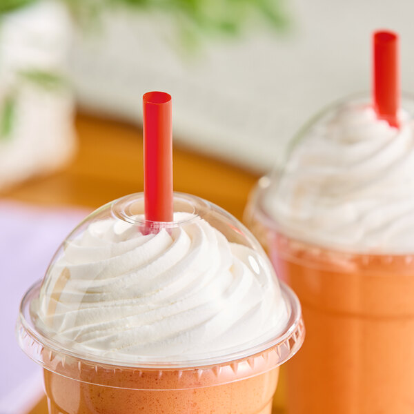 A red pointed smoothie straw inserted into a plastic cup with a dome lid and whipped topping.