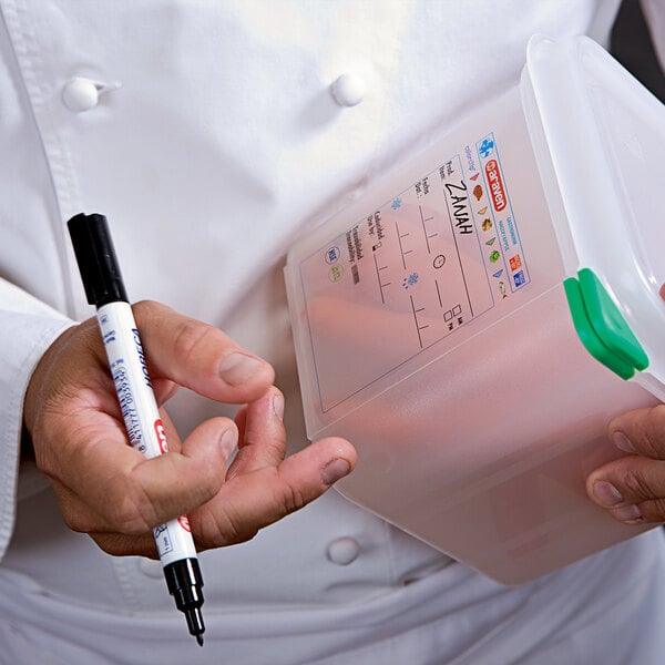 A chef using an Araven black food safe marker to label a container of food.