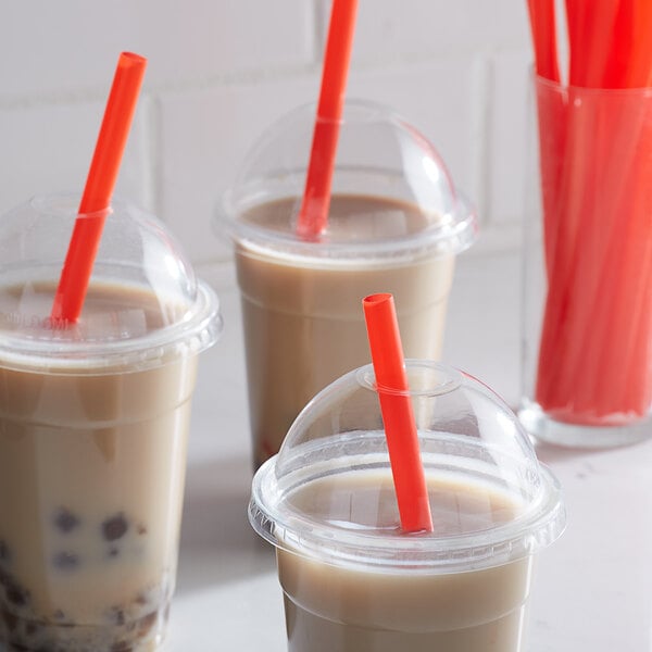 Three plastic cups of iced drinks with red straws and orange lids.