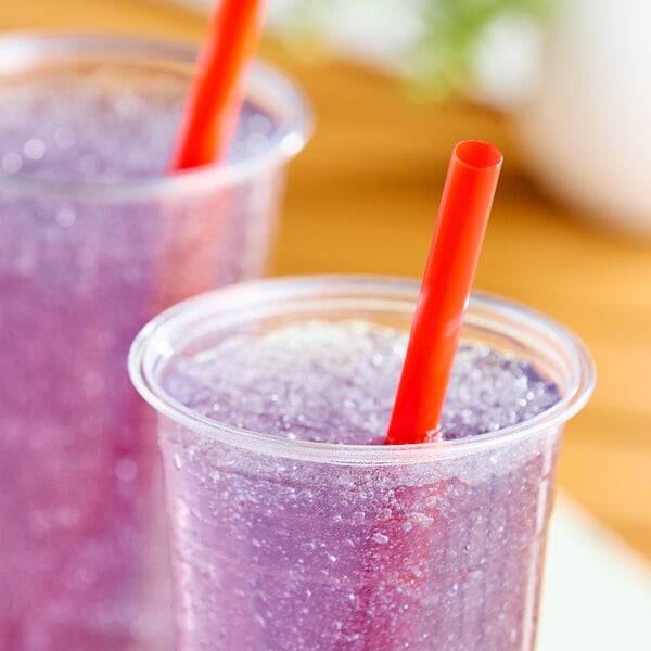 A clear plastic cup filled with a purple slushy drink and a red pointed straw.