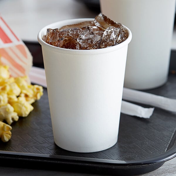 A white Choice paper cold cup filled with ice on a tray with popcorn.