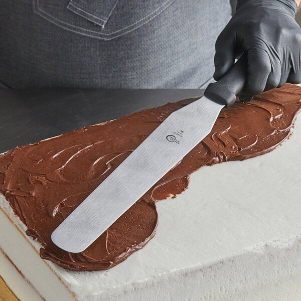 a person with a spatula on a cake