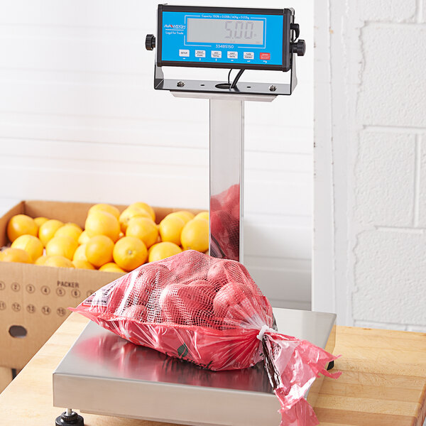 A stainless steel AvaWeigh tower on a counter with a bag of oranges on the scale.