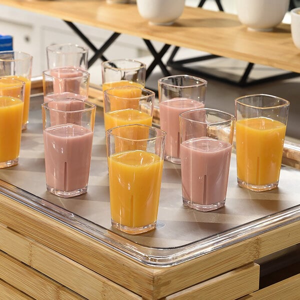 A tray of Front of the House Drinkwise Mod plastic shot glasses filled with orange and pink liquid.