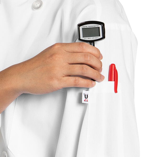 A person wearing a white Uncommon Chef long sleeve chef coat with a digital thermometer in their pocket.