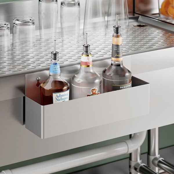 A 15-inch Steelton stainless steel single tier speed rail mounted to a bar counter holding three liquor bottles.