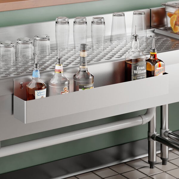 A 30-inch stainless steel single tier speed rail mounted to a bar setup, holding several liquor bottles.