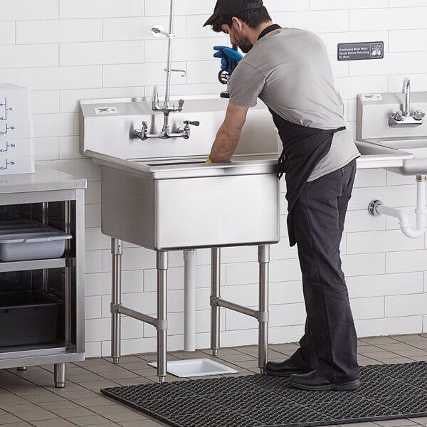A man in an apron washing a Regency commercial sink.