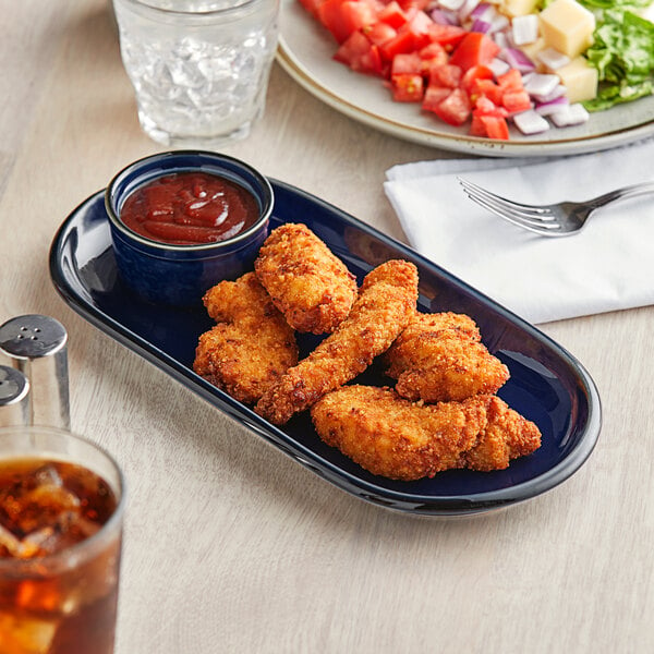 An Acopa Azora Blue stoneware platter with fried chicken wings and salad on a table.