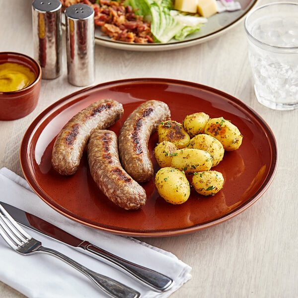 A plate of sausages and potatoes on an Acopa Sedona Orange stoneware plate.