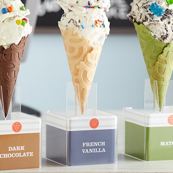 A white Konery French Vanilla waffle cone stand holding three ice cream cones.