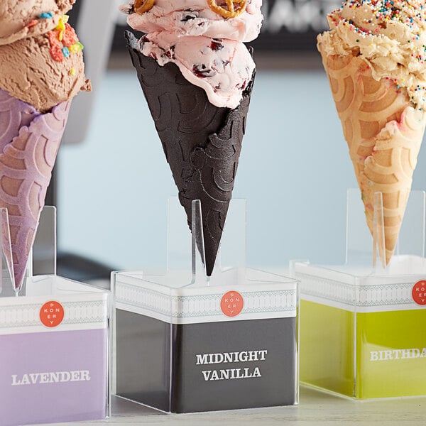 A Konery Midnight Black waffle cone stand holding three ice cream cones on a counter.