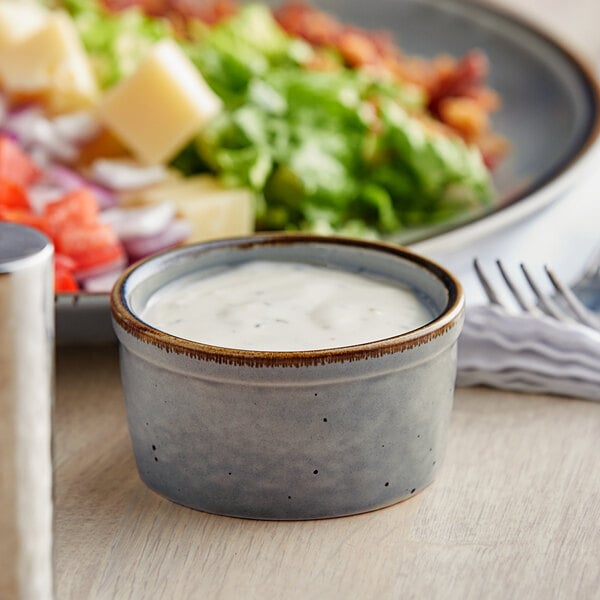 A granite gray Acopa stoneware ramekin filled with sauce on a table.