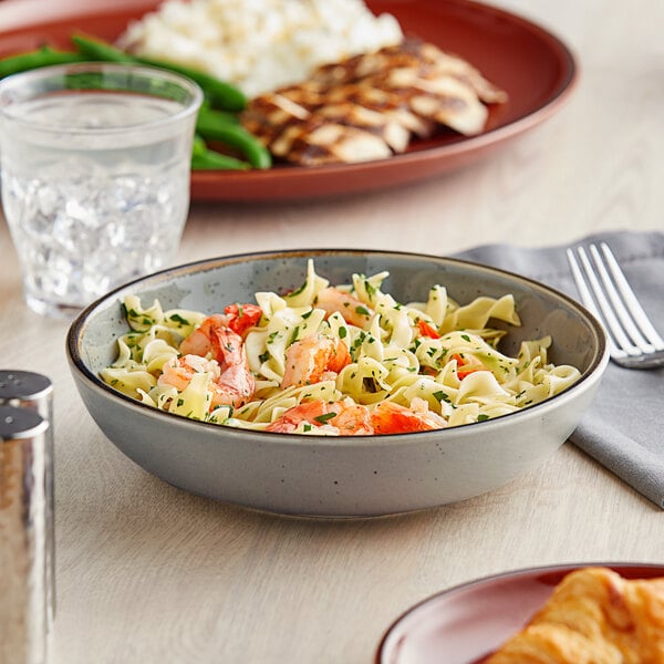 An Acopa Keystone stoneware bowl filled with pasta and shrimp with a fork.