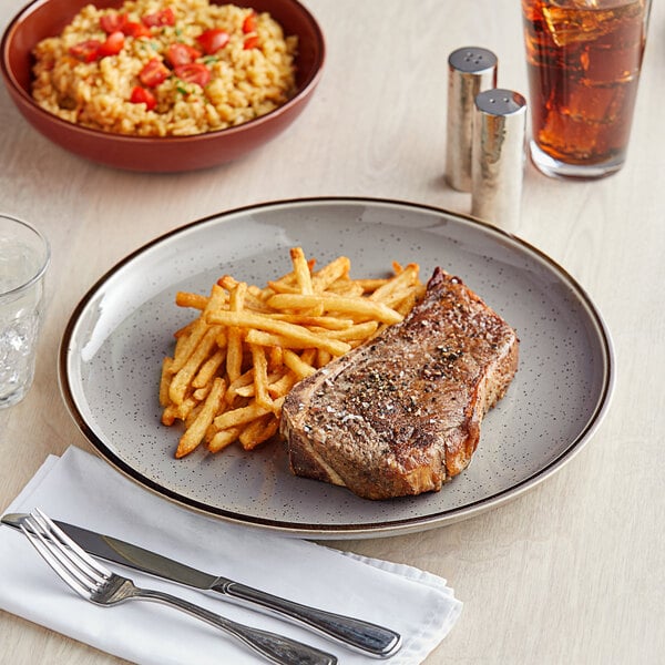 An Acopa Keystone stoneware plate with steak and french fries on it.