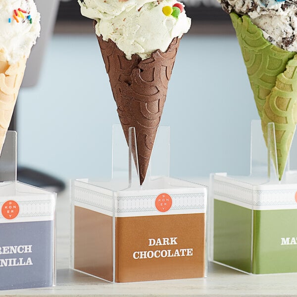 A Konery dark chocolate waffle cone stand with three ice cream cones in it.