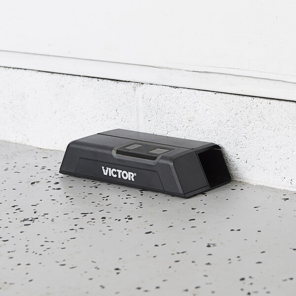 A black rectangular Victor Pest M1 Smart-Kill Electronic Mouse Trap with white text on the floor.