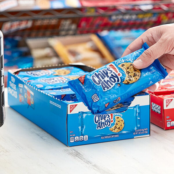 A hand holding a small blue package of Nabisco Chips Ahoy! chocolate chip cookies.