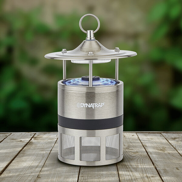 A silver and black round metal lantern with a decorative top sitting on a wooden table.