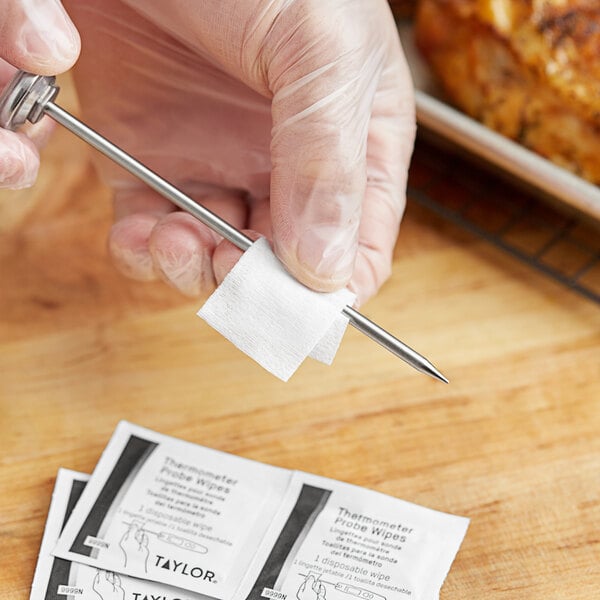 A person holding a small metal object and a piece of paper.