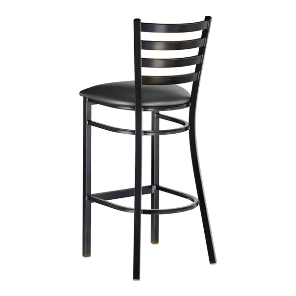 A metal bar stool with a distressed copper finish, ladder back design, and a black vinyl padded seat.