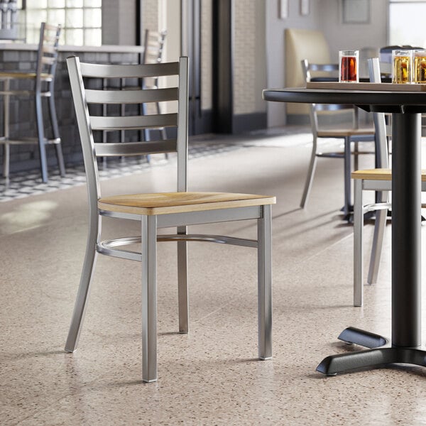 A Lancaster Table & Seating clear coat finish ladder back chair with a driftwood seat on a table with drinks.