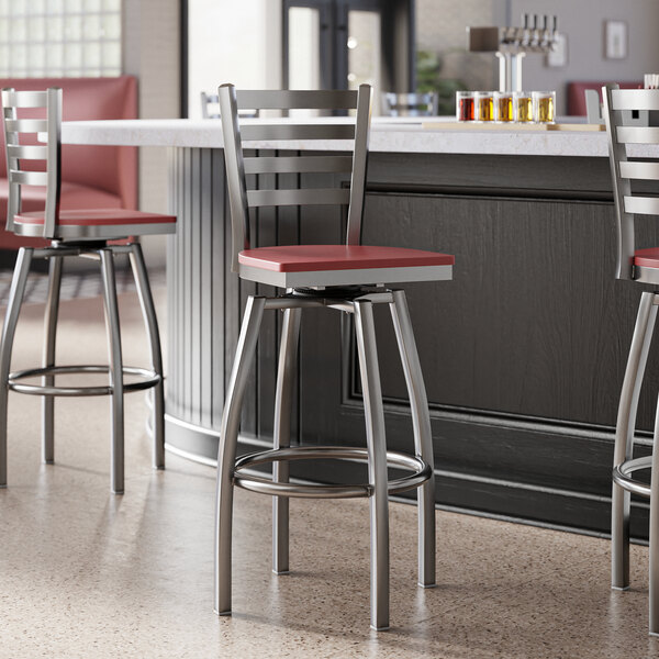 A group of Lancaster Table & Seating bar stools with mahogany seats at a counter in a restaurant.