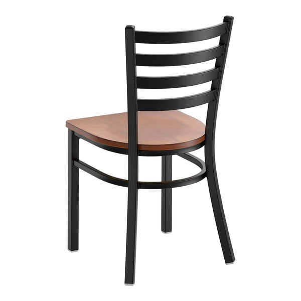 A black metal ladder back chair with an antique walnut wood seat.