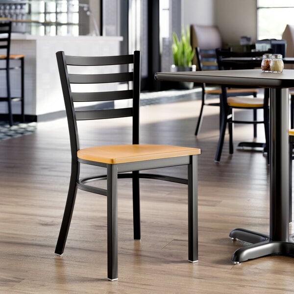 A black ladder back chair with a natural wood seat, designed for dining or restaurant use.