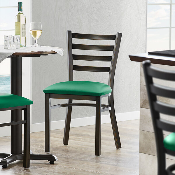 A Lancaster Table & Seating distressed copper ladder back chair with a green vinyl cushion on a table with wine bottles and glasses.