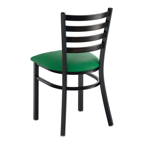A black ladder back chair with a green vinyl padded seat and a distressed copper finish.