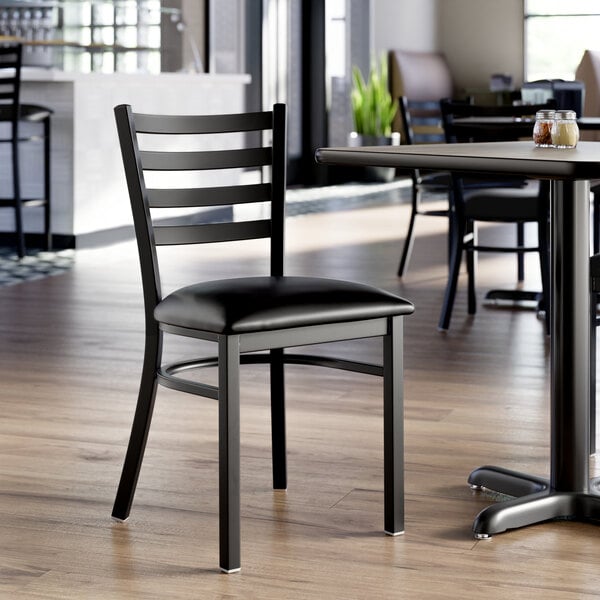 A black ladder back chair with a 2 1/2 inch black vinyl padded seat and a detached seat design.