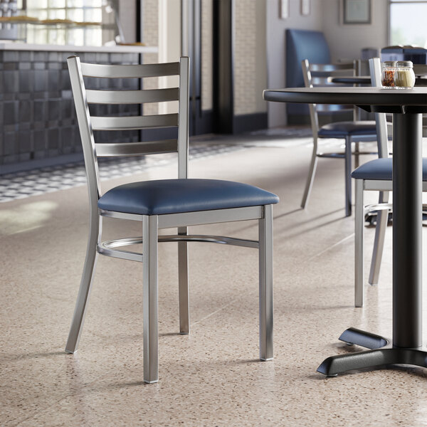 A Lancaster Table & Seating clear coat finish ladder back chair with navy vinyl padded seat on a table in a restaurant.