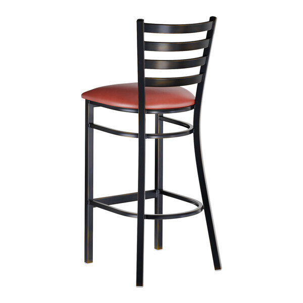 A metal bar stool with a ladder back design and a burgundy vinyl padded seat.