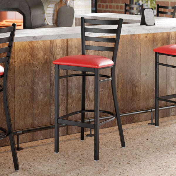 Lancaster Table & Seating Black Finish Ladder Back Bar Stool with 2 1/2" Red Vinyl Padded Seat